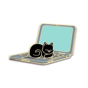 May include: Gold-tone enamel pin of a black cat sleeping on a laptop computer. The cat is curled up on the keyboard and the laptop screen is light blue.