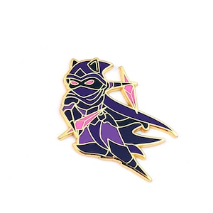 May include: A gold-colored enamel pin featuring a purple and pink cartoon character wearing a hooded cloak and holding a pink crystal. The character has cat ears and a mask.