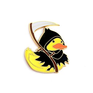 May include: A gold-coloured enamel pin of a yellow rubber duck wearing a black hooded robe and holding a scythe.