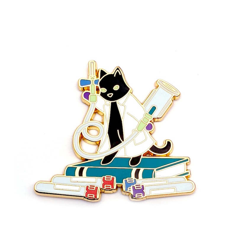 May include: Gold enamel pin featuring a black cat wearing a white lab coat and holding a syringe. The cat is sitting on a stack of books with test tubes in front of it.