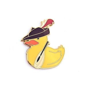 May include: A yellow duck pin with a black hat, red feather, and a musical instrument. The pin has a gold outline and is set against a white background. The duck has an orange beak.