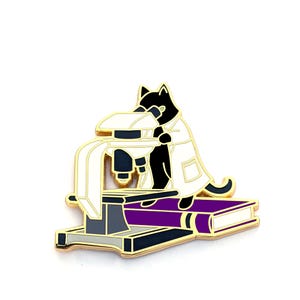 May include: A black cat wearing a white lab coat is looking through a microscope. The microscope is sitting on a purple book.