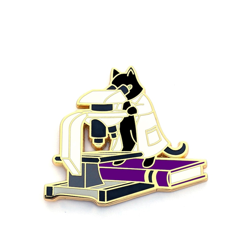 May include: A black cat wearing a white lab coat is looking through a microscope. The microscope is sitting on a purple book.