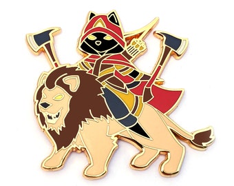 May include: A gold-colored enamel pin featuring a black cat wearing a red hooded cloak and riding a lion. The cat is holding a bow and arrow and the lion has a fierce expression.