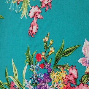 May include: A vibrant turquoise fabric featuring a floral pattern. The design includes various flowers in shades of pink, purple, red, and yellow, with green leaves. The flowers are scattered across the fabric.