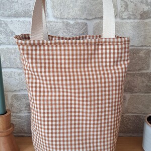 Peut inclure: Un sac fourre-tout en tissu gingham brun et blanc avec des anses cr&egrave;me.