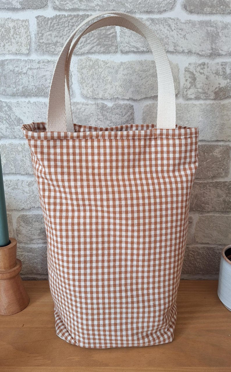 Peut inclure: Un sac fourre-tout en tissu gingham brun et blanc avec des anses cr&egrave;me.