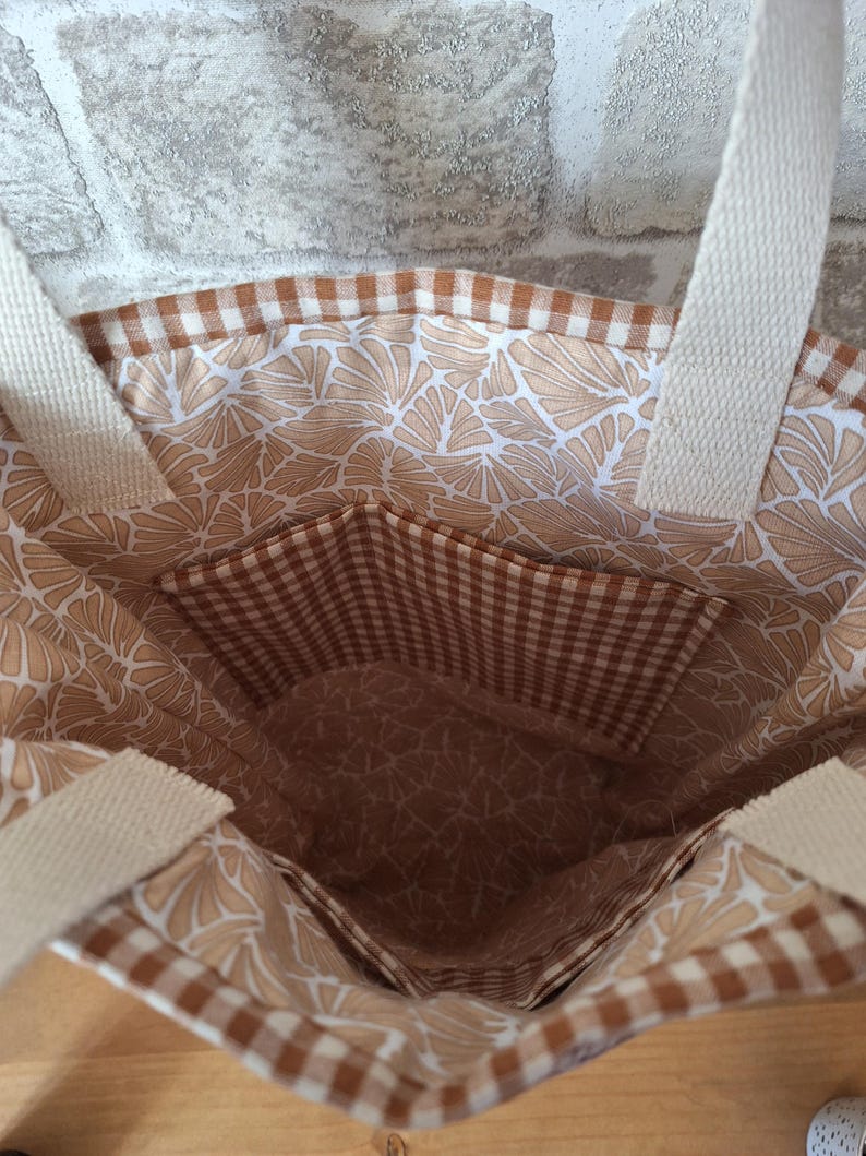 Peut inclure: Un sac fourre-tout brun et blanc avec un motif vichy et un imprim&eacute; floral. Le sac a une grande poche &agrave; l'int&eacute;rieur.