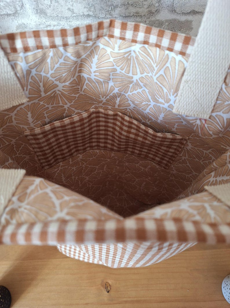 Peut inclure: Un sac cabas en vichy brun et blanc avec une doublure &agrave; imprim&eacute; floral brun et blanc. Le sac a une petite poche int&eacute;rieure en vichy brun et blanc.