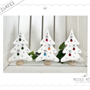May include: Three white felt Christmas trees with silver glitter and embroidered ornaments. Each tree has a different colour scheme: green, red, and blue. The trees are standing on a white wooden surface.
