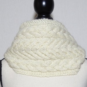 May include: A white knitted cowl neck scarf with a cable knit pattern.