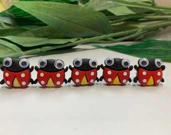 May include: Five red and black ladybug-shaped buttons with white polka dots and googly eyes.
