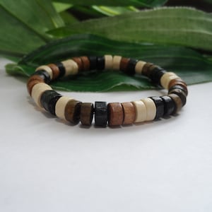 May include: A wooden bracelet with brown, black, and white beads. The bracelet is made of natural wood and has a simple, elegant design.
