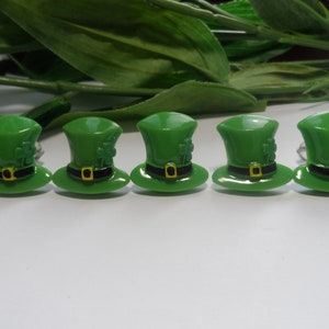 May include: Five green leprechaun hats with black bands and gold buckles. Each hat has a shamrock design.
