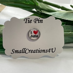 May include: A silver tie pin with a red heart and the words "I love Jesus" on a white card with the text "Tie Pin" and "SmallCreations4U".