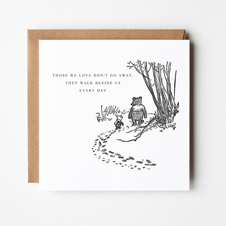 Puede incluir: Tarjeta de felicitaci&oacute;n cuadrada con sobre marr&oacute;n. La tarjeta presenta una ilustraci&oacute;n en blanco y negro de Winnie the Pooh y Piglet caminando por un sendero. El texto sobre la ilustraci&oacute;n dice: "AQUELLOS QUE AMAMOS NO SE VAN, CAMINAN A NUESTRO LADO CADA D&Iacute;A."