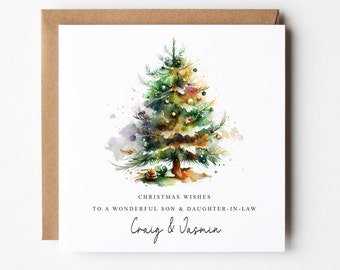 Op de afbeelding: Een kerstkaart met een aquarel van een versierde kerstboom. De kaart bevat de tekst "CHRISTMAS WISHES TO A WONDERFUL SON & DAUGHTER-IN-LAW" en de namen "Craig & Jasmin". De kaart heeft een bruine envelop.