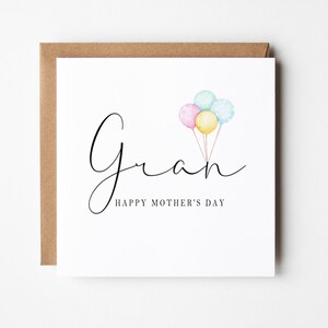 May include: A white card with the word "Gran" written in black cursive script. Three watercolor balloons in pink, blue, and yellow are floating above the word. The text "Happy Mother's Day" is written below the word "Gran".