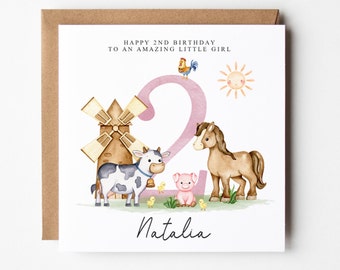 May include: A pink and white birthday card with a watercolor illustration of a farm scene. The number 2 is in the center of the card with a windmill, cow, horse, pig, and chicks around it. The text "Happy 2nd Birthday to an amazing little girl" is at the top of the card and the name "Natalia" is at the bottom.