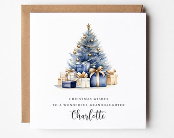 Op de afbeelding: Een kerstkaart met een aquarel-illustratie van een blauwe kerstboom met gouden ornamenten en cadeaus. De tekst luidt "Kerstgroeten aan een prachtige kleindochter Charlotte".