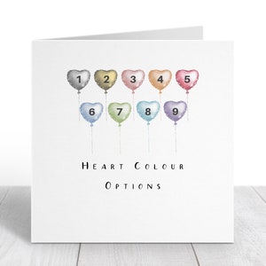 K&ouml;nnte beinhalten: Eine Karte mit neun herzf&ouml;rmigen Ballons in verschiedenen Farben, nummeriert von 1 bis 9. Der Text "HEART COLOUR OPTIONS" ist unter den Ballons gedruckt.