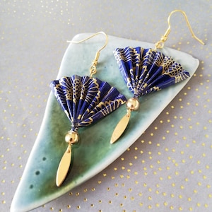 Op de afbeelding: Een paar blauwe en gouden origami-waaier oorbellen met gouden kralenaccenten en gouden haken.