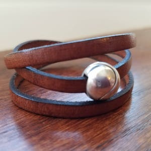 May include: A brown leather wrap bracelet with a silver ball clasp.