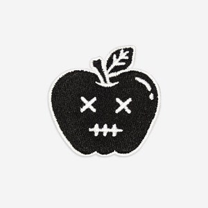 May include: Black and white embroidered patch of an apple with stitched eyes and mouth. The apple has a stem and leaf.