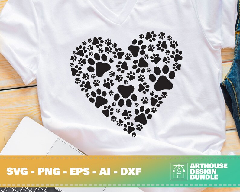 May include: A white t-shirt with a black paw print design in the shape of a heart. The design is made up of many paw prints of different sizes. The text "SVG - PNG - EPS - AI - DXF" is at the bottom of the image.