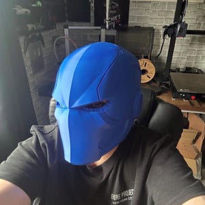 May include: A striking blue helmet with a modern, angular design. The helmet has a central stripe and side features, possibly for a futuristic or superhero aesthetic. The wearer is wearing a black t-shirt with the text "FUTURE PROJECT NEW YORK CITY".