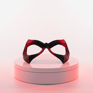 May include: A dark red, angular eye mask with a pointed bridge and wide, contoured openings for the eyes. The mask features a smooth, solid finish with sharp geometric edges and a symmetrical design that tapers toward the outer temples.