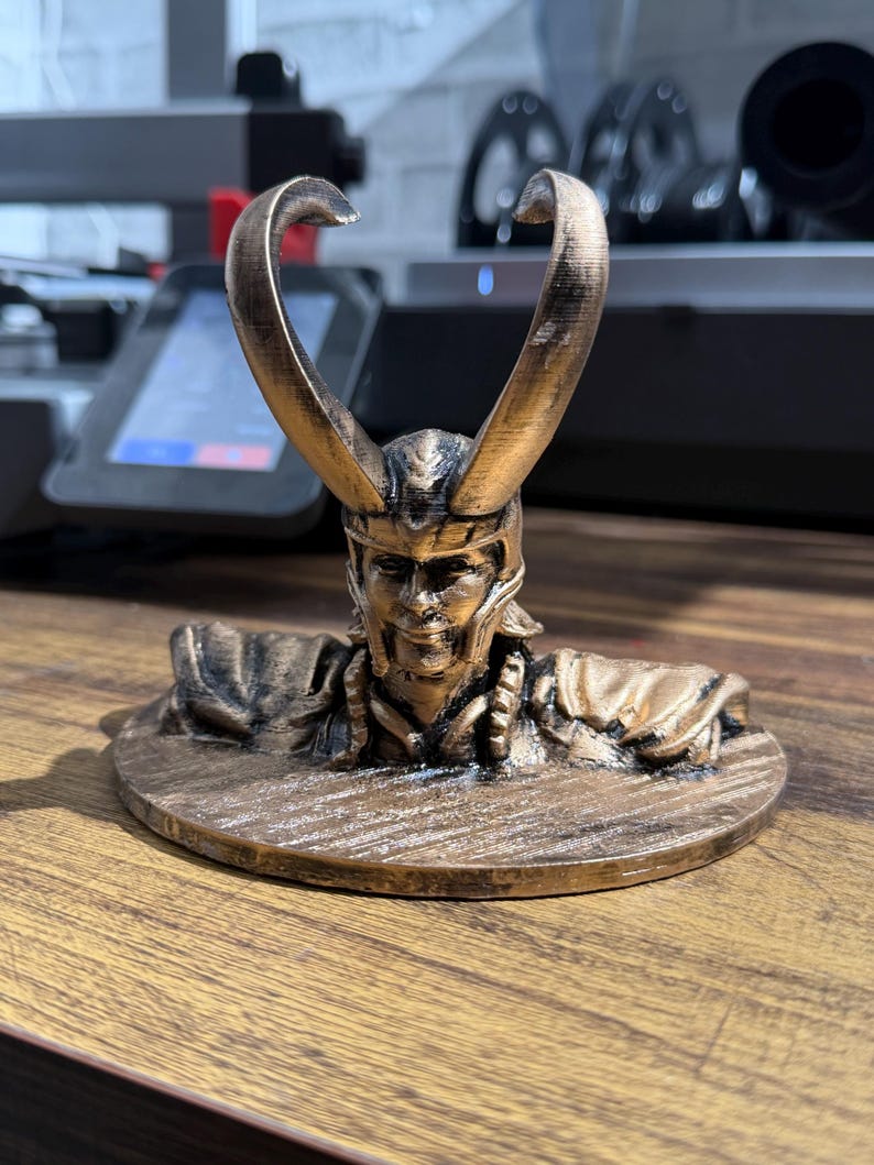 May include: A bronze-colored figurine of a horned character, possibly a mythological figure or a character from a fantasy story. The figurine is on a round base and has intricate details.