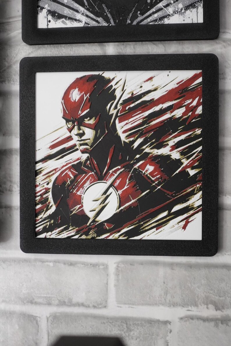 May include: A square framed wall art piece featuring a stylized illustration of The Flash in a red and black suit with a white lightning bolt emblem on the chest. The artwork uses dynamic, streaking brushstroke effects in red, black, and white.