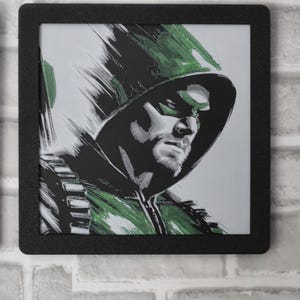 May include: A square black frame containing a stylized illustration of a hooded figure wearing a green mask and green attire. The artwork features bold, expressive brushstrokes in shades of green, black, and white, depicting a focused facial expression.