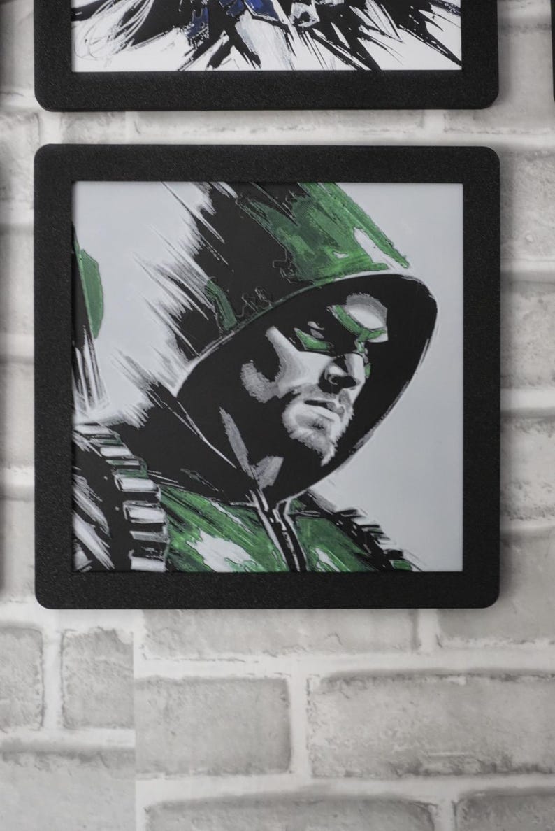 May include: A square black frame containing a stylized illustration of a hooded figure wearing a green mask and green attire. The artwork features bold, expressive brushstrokes in shades of green, black, and white, depicting a focused facial expression.