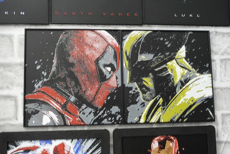 May include: Two rectangular framed wall art pieces featuring stylized graphic illustrations. The left piece depicts a red and black masked character in profile, while the right piece shows a yellow and black masked character in profile.