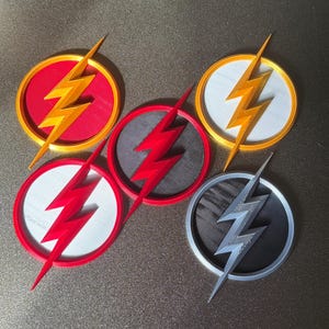 May include: Five circular coasters featuring the Flash logo. The coasters have a red, yellow, white, and gray color scheme. Each coaster has a lightning bolt design in the center.