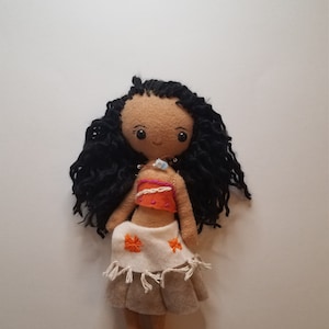 May include: Handmade felt doll with long black curly hair, wearing an orange and white top and a brown skirt with orange flowers.