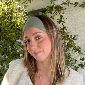 Peut inclure: Une femme portant un bandeau vert clair et une veste en fourrure blanche. Elle porte un collier en or avec des accents de perles.