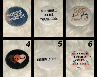 May include: Ten round button badges with various sayings and designs. The badges are white, black, and blue with gold glitter accents. The sayings include "Thick Thighs Thin Patience", "But First... Let Me Thank God", "God Don't Play About Me", "Equal", "Entrepreneur Her", and "My Name Is Peaches And I'm The Best..."