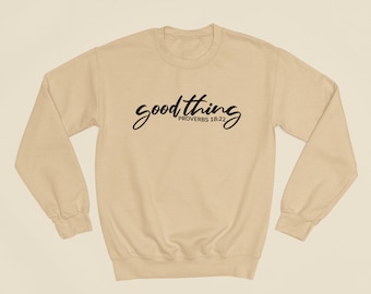 May include: A beige sweatshirt with the text "good thing PROVERBS 18:22" printed in black.