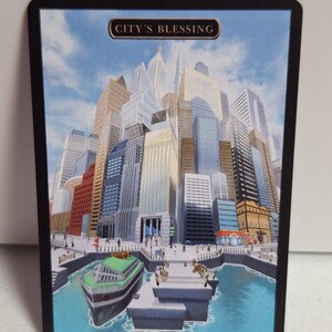 May include: A trading card featuring a cityscape illustration with a blue sky background. The card has a black border and the text "CITY'S BLESSING" at the top. A boat is in the foreground, and the city has many tall buildings.