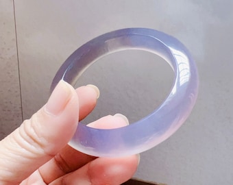 May include: A light purple jade bangle bracelet. The bangle is smooth and polished.