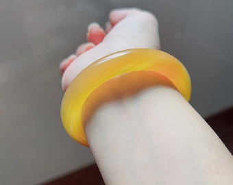 May include: A yellow bangle bracelet made of polished stone.