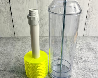 May include: A clear plastic dispenser with a lid and a metal rod. The dispenser is sitting on a yellow plastic base with a white pipe.