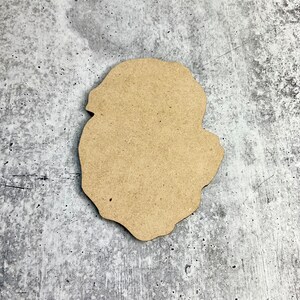 May include: A brown, irregularly shaped wooden cutout, resembling a cloud or a leaf, on a gray textured background.