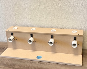 May include: A wooden stand with four white PVC pipes and black switches. The stand has a shelf on the bottom and is designed for holding and drying items.