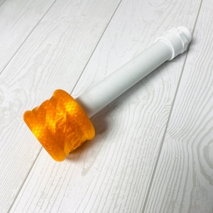 May include: A white plastic pipe with a yellow 3D printed adapter. The adapter has a textured surface and the word "KITZ" printed on it.