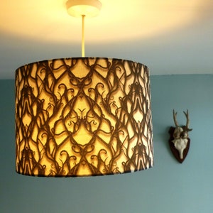 May include: A brown and cream lampshade with a black and white patterned design. The pattern is a repeating design of vines and leaves.