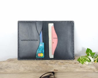 May include: Open black leather wallet with visible stitching, holding a credit card and a document. The wallet is rectangular with rounded corners and a contrasting light-colored interior. The wallet is open, displaying the contents.